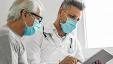 Healthcare provider and patient sitting next to each other while looking at a tablet