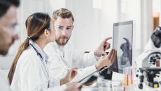 Two people standing in a laboratory looking at a computer