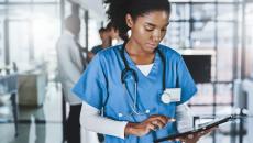 Healthcare professional in scrubs looking at a tablet