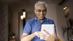 Person at home smiling and looking at a tablet