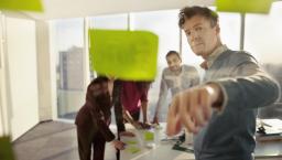 People standing in a room looking at a wall of post-its