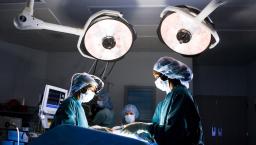 Surgeons standing around an operating table performing surgery