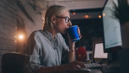 Person sitting at their computer drinking something out of a coffee cup