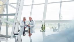 Two healthcare providers standing in a room in front of large windows