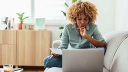 Individual sitting on a couch and looking at a computer