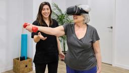 Person doing rehabilitation exercises while wearing a headset and standing next to a PT