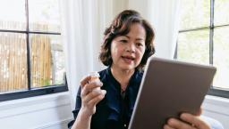 Person holding a tablet in one hand and a prescription bottle in the other