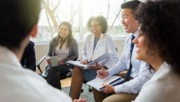 Five business people sitting on chairs in a circle 