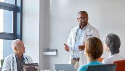 Healthcare provider standing in front of three other people in a meeting room