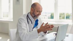 Doctor sitting at a desk while looking at a computer screen