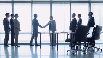 Business officials shake hands to close a deal