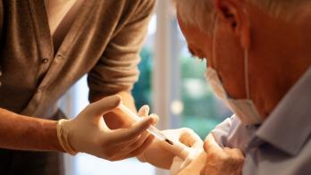 Healthcare practitioners administering injection to patient