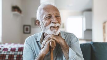 Person sitting on their ouch while holding their cane