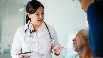 Healthcare provider standing beside a patient and their loved one