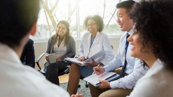 Five business people sitting on chairs in a circle 