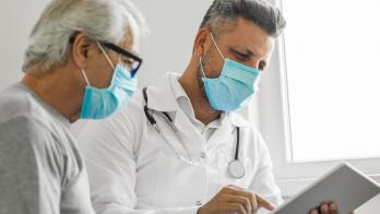 Healthcare provider and patient sitting next to each other while looking at a tablet