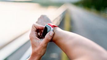 Person's arms with one hand playing with an Apple Watch