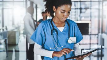 Healthcare professional in scrubs looking at a tablet