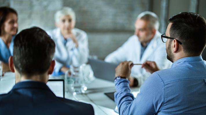 Five people sitting around a table speaking with each other