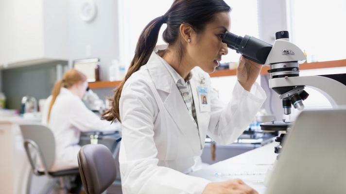 Scientist in a lab looking into a microscope