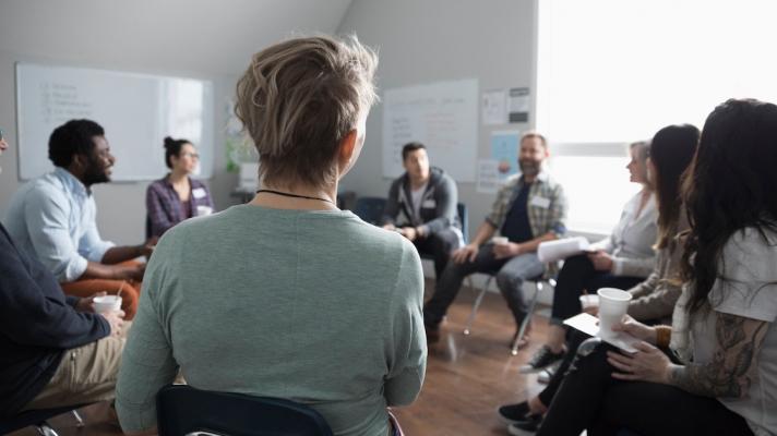 Group of people sitting in a room in a circle