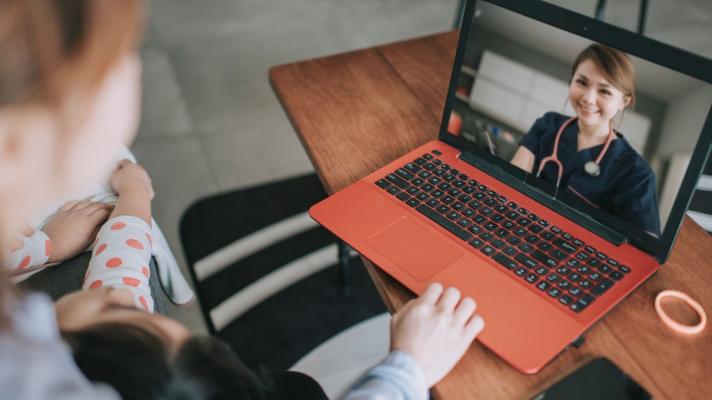 Telehealth provider on a computer with two people sitting on a couch looking at the computer