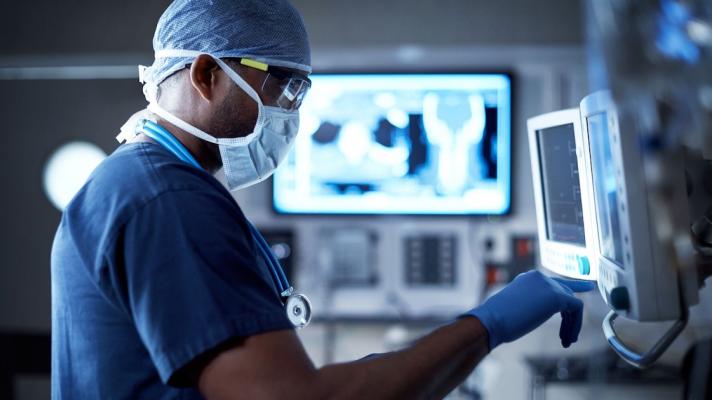 Doctor in scrubs standing in front of computer screens