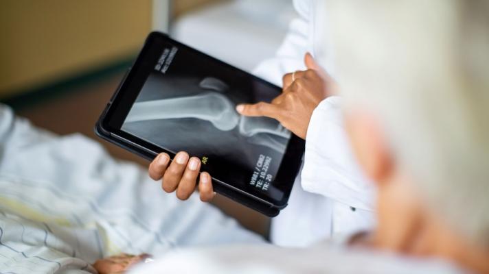 A doctor holding a digital tablet showing a patient their bone X-ray